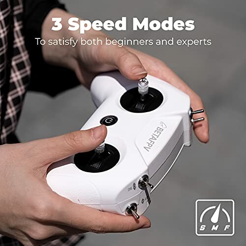 Hands holding a drone controller with 3 speed modes.