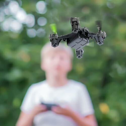 Child controlling a flying drone outdoors